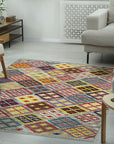 Nadia Kilim Multicolor Flatweave Wool Rug displayed on a light wood floor, its vibrant geometric patterns of red, blue, yellow, and green adding a bohemian touch to a modern setting.