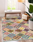 Nadia Kilim Multicolor Flatweave Wool Rug, a vibrant patchwork of geometric patterns in warm and cool tones, lays flat on a light wood floor. The rug's handcrafted wool construction radiates inviting textures, adding warmth and artistry to the space.
