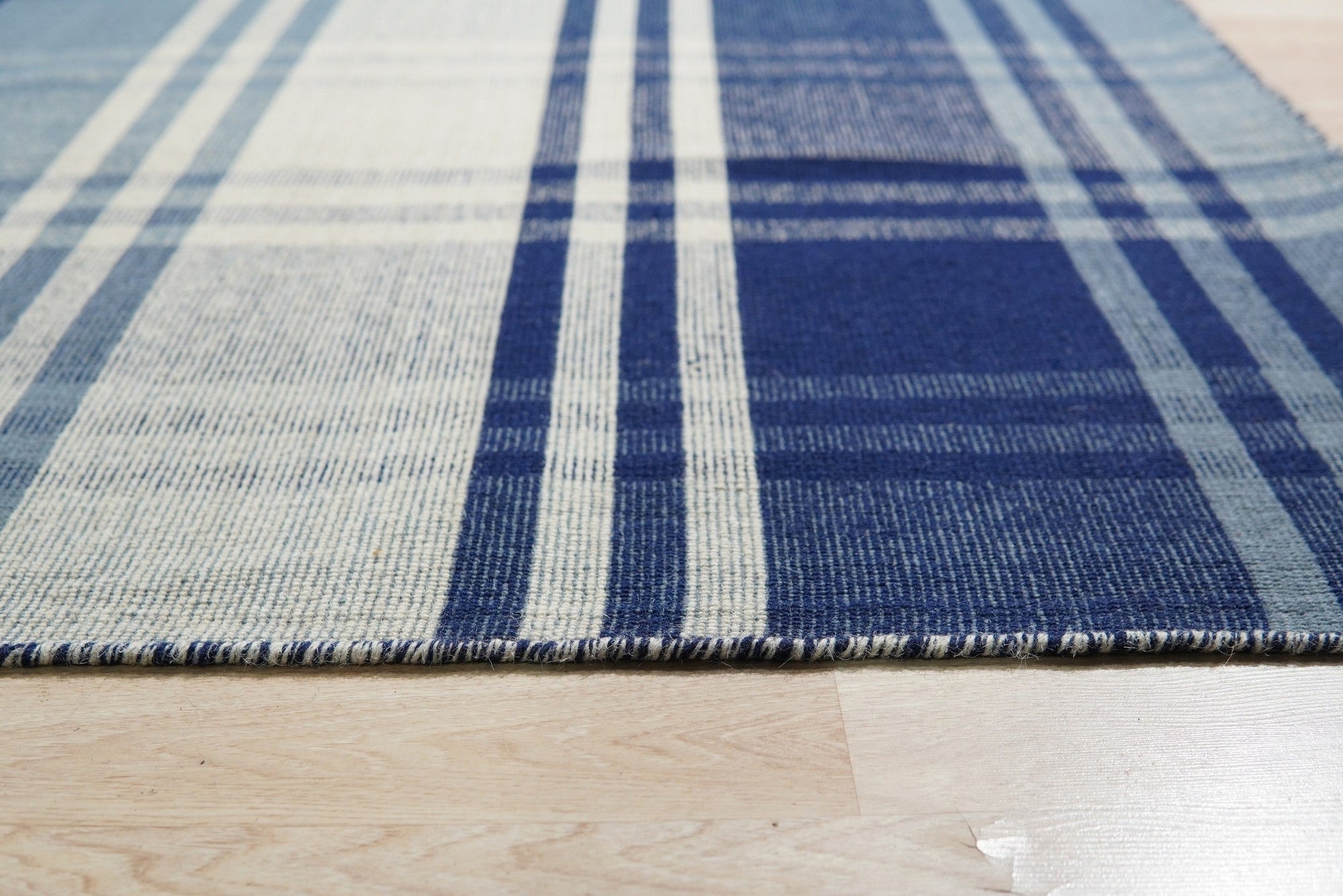 Sophisticated Elegant Blue Flatweave Wool Rug, its cool blues and elegant weave grounding a bright, airy living space with modern furniture.
