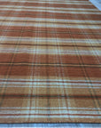 Cassandra Stylish Orange Flatweave Wool Rug, a vibrant orange flatweave wool rug with a geometric pattern, displayed on a light wooden floor in a bright, modern living space.