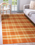 Cassandra Stylish Orange Flatweave Wool Rug in a bright, naturally lit living room setting, showcasing its vibrant orange hues and flatweave construction alongside neutral furniture and decor.