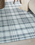 Jasmine Stylish Gray Flatweave Wool Rug graces a warmly lit living room; its subtle gray tones and flatweave construction anchoring a cozy seating arrangement with a mid-century modern sofa and minimalist decor.