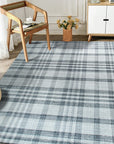 Jasmine Stylish Gray Flatweave Wool Rug displayed in a bright, modern living room setting. Its flatweave construction allows other furniture such as a stylish coffee table and dark-colored couch to effortlessly stand on it.