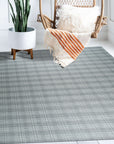 Classic Radiant Gray Flatweave Wool Rug, its subtle gray tones and flatweave texture complementing a bright, modern living room with a white sofa and light wood coffee table.