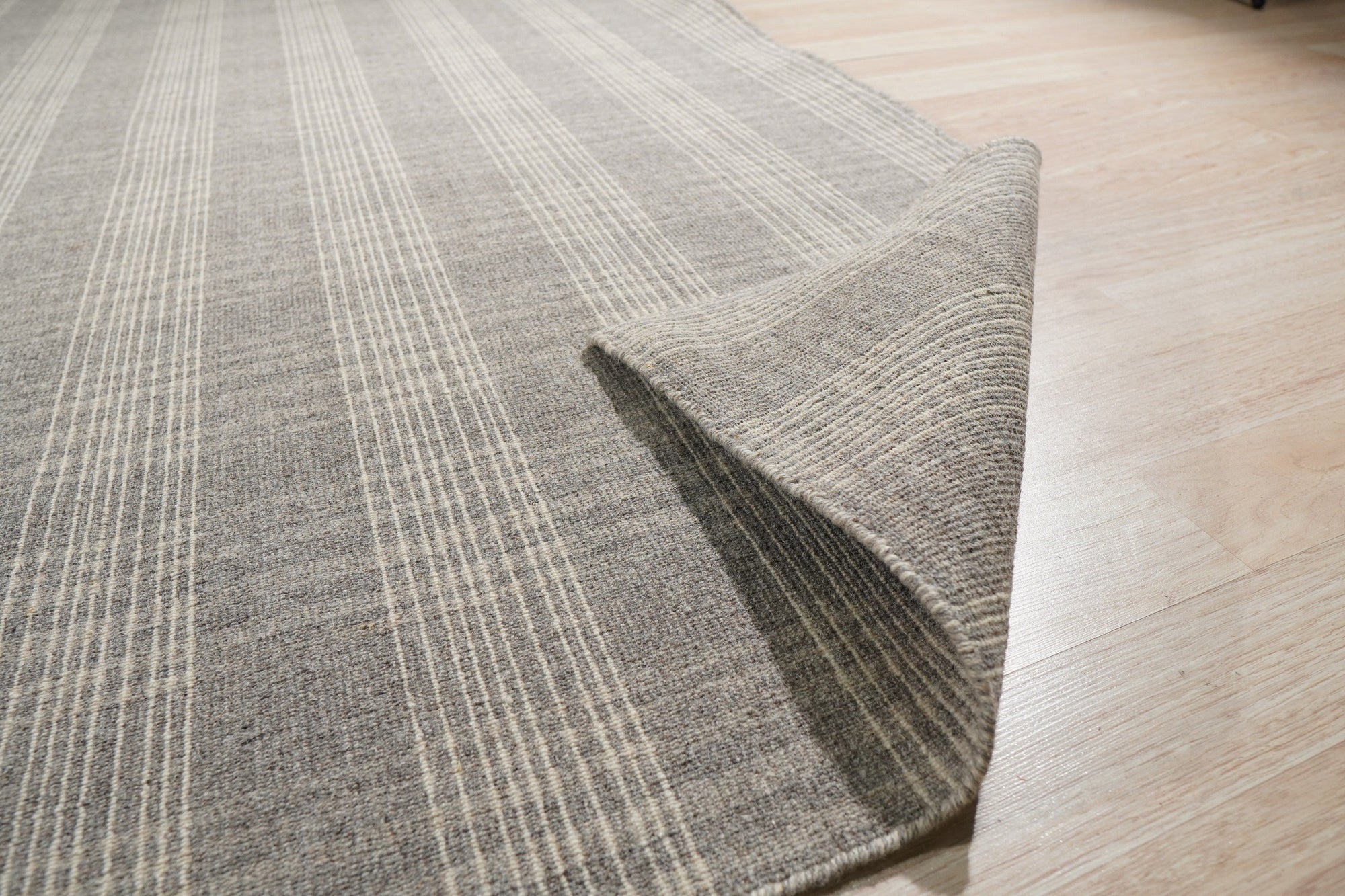 Classic Radiant Gray Flatweave Wool Rug graces a warmly lit living room; soft gray wool, flatweave construction visible, anchors a seating area with modern furniture.