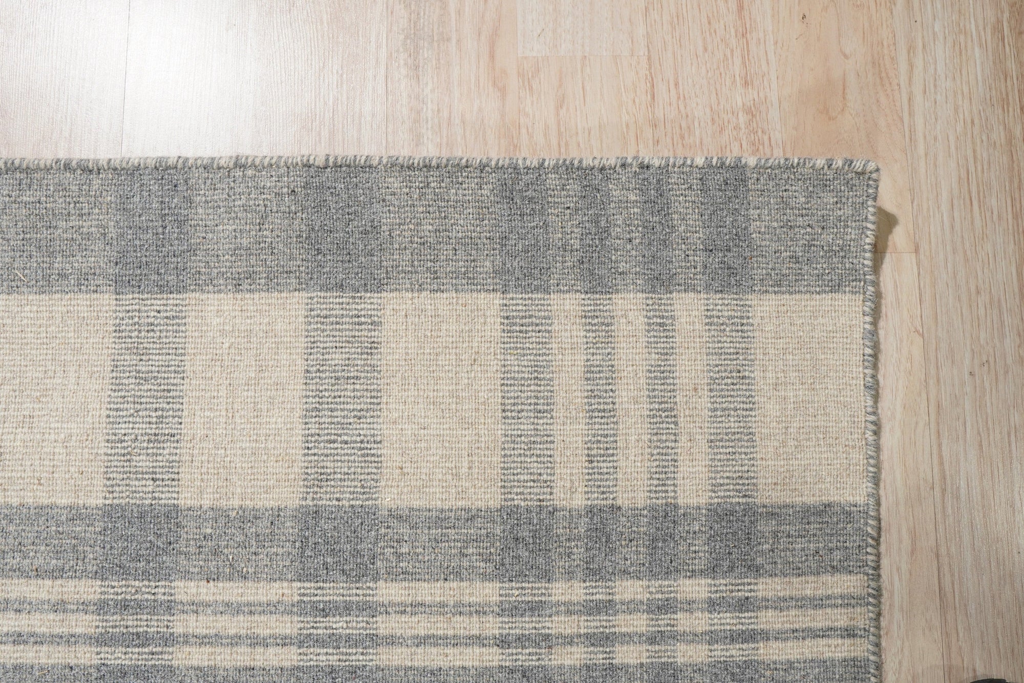 Handcrafted Vibrant Gray Flatweave Wool Rug displayed on a light wooden floor, its gray tones subtly shifting with the light, a testament to its flatweave wool construction.