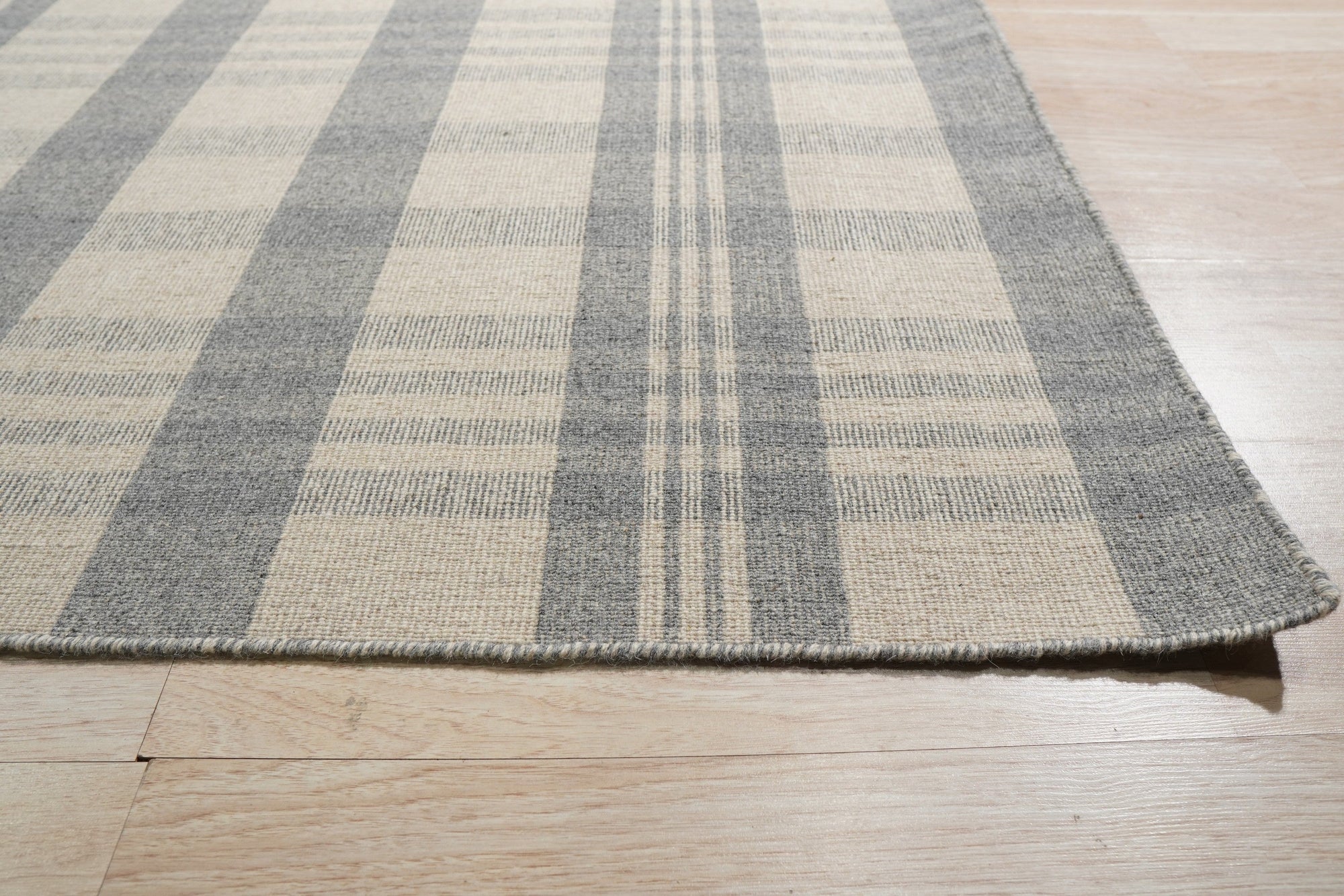 Handcrafted Vibrant Gray Flatweave Wool Rug, woven in a flatweave style, dominates a modern living space, its subtle gray tones grounding the room beneath minimalist furniture.