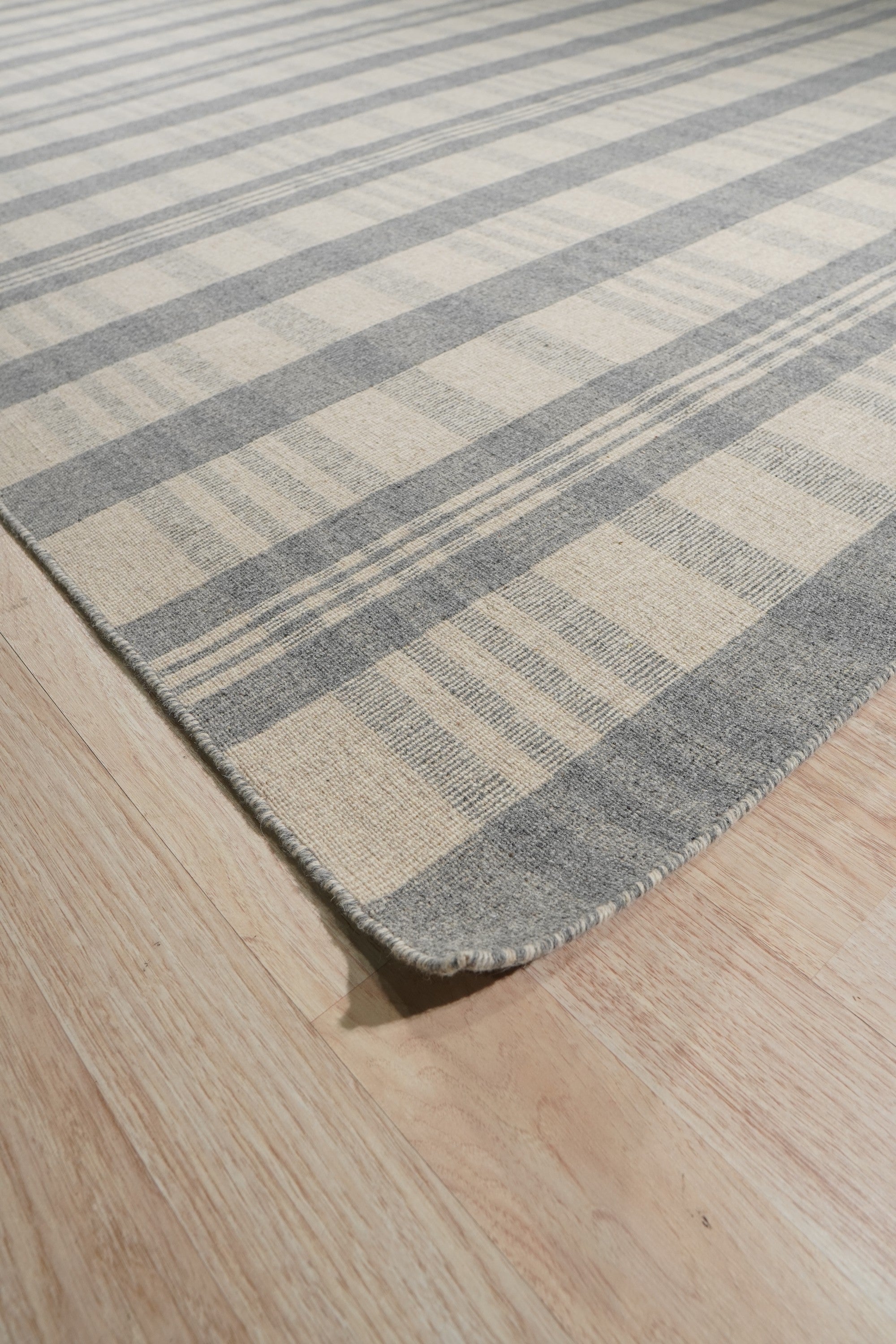 Handcrafted Vibrant Gray Flatweave Wool Rug displayed in a bright, modern living room. Gray and white geometric patterns create a contemporary feel on this flatweave wool rug, anchoring the space.