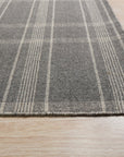 Graceful Quinn Gray Flatweave Wool Rug, showcasing a subtle geometric pattern in shades of gray, lies elegantly on a light-colored wood floor in a bright, minimalist room.
