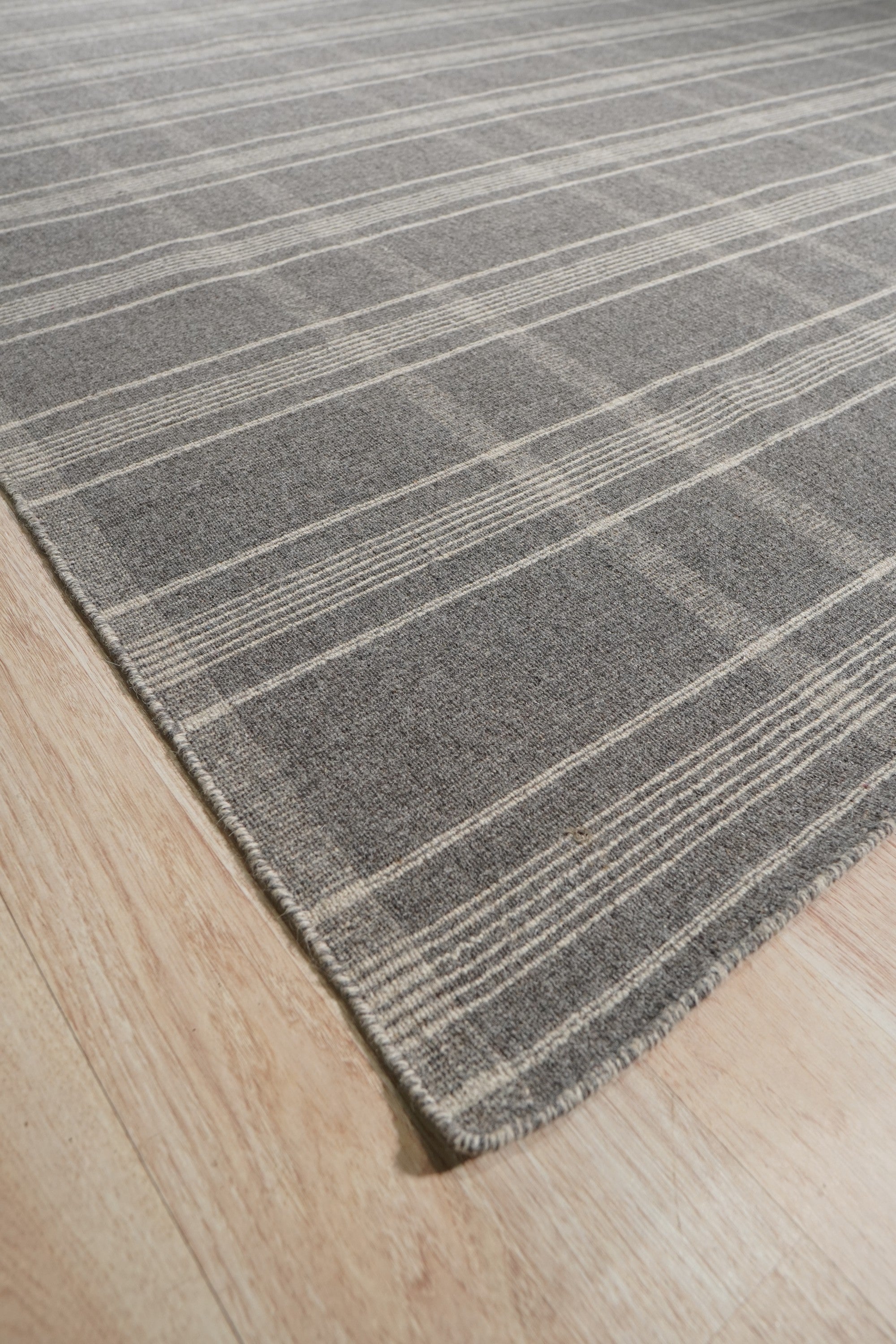 Graceful Quinn Gray Flatweave Wool Rug, showcasing its subtle geometric pattern and flatweave construction in a warmly lit interior setting.
