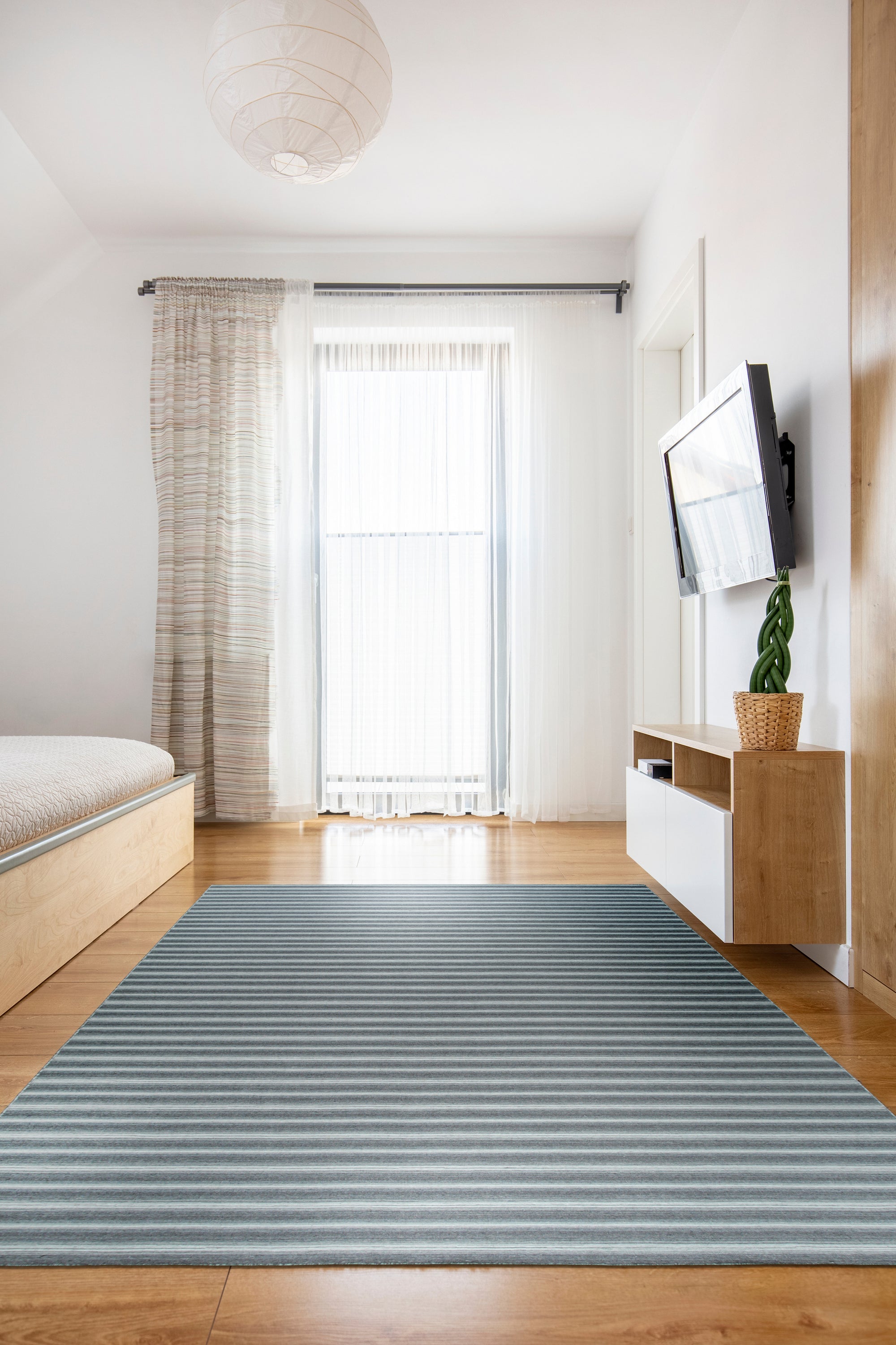 Lush Timeless Gray Flatweave Wool Rug, woven in a flatweave construction, rests on a light wood floor. Soft, diffused light highlights the rug's subtle gray tones and textured surface.