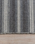 Lush Timeless Gray Flatweave Wool Rug, a gray wool rug with a subtly textured flatweave design, sprawls elegantly on a light hardwood floor, enhancing a modern living room setup with a sofa and minimalist decor.