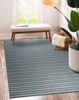 Lush Timeless Gray Flatweave Wool Rug, soft gray hues and subtle texture create a calming atmosphere in a bright, minimalist living room setting with a light wood floor.