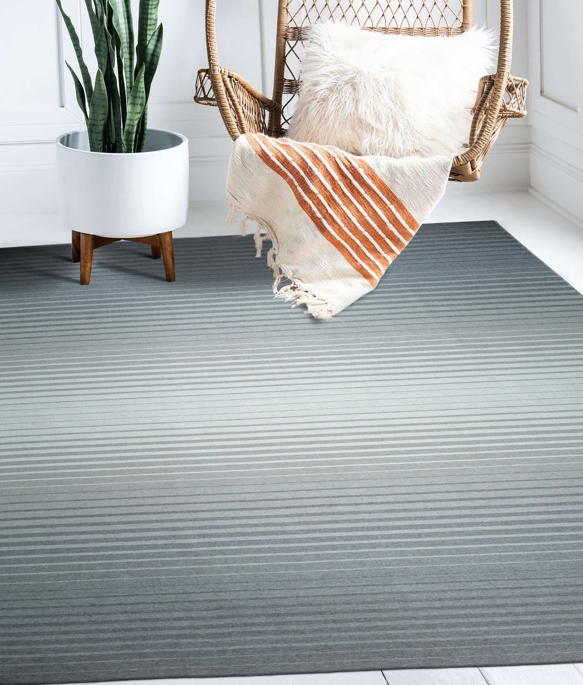 Timeless Comfortable Gray Flatweave Wool Rug, a soft gray wool rug with a subtle flatweave texture, warming a neutral living room with a light wood coffee table and a glimpse of a cozy couch.