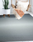 Timeless Comfortable Gray Flatweave Wool Rug, a soft gray wool rug with a subtle flatweave texture, warming a neutral living room with a light wood coffee table and a glimpse of a cozy couch.