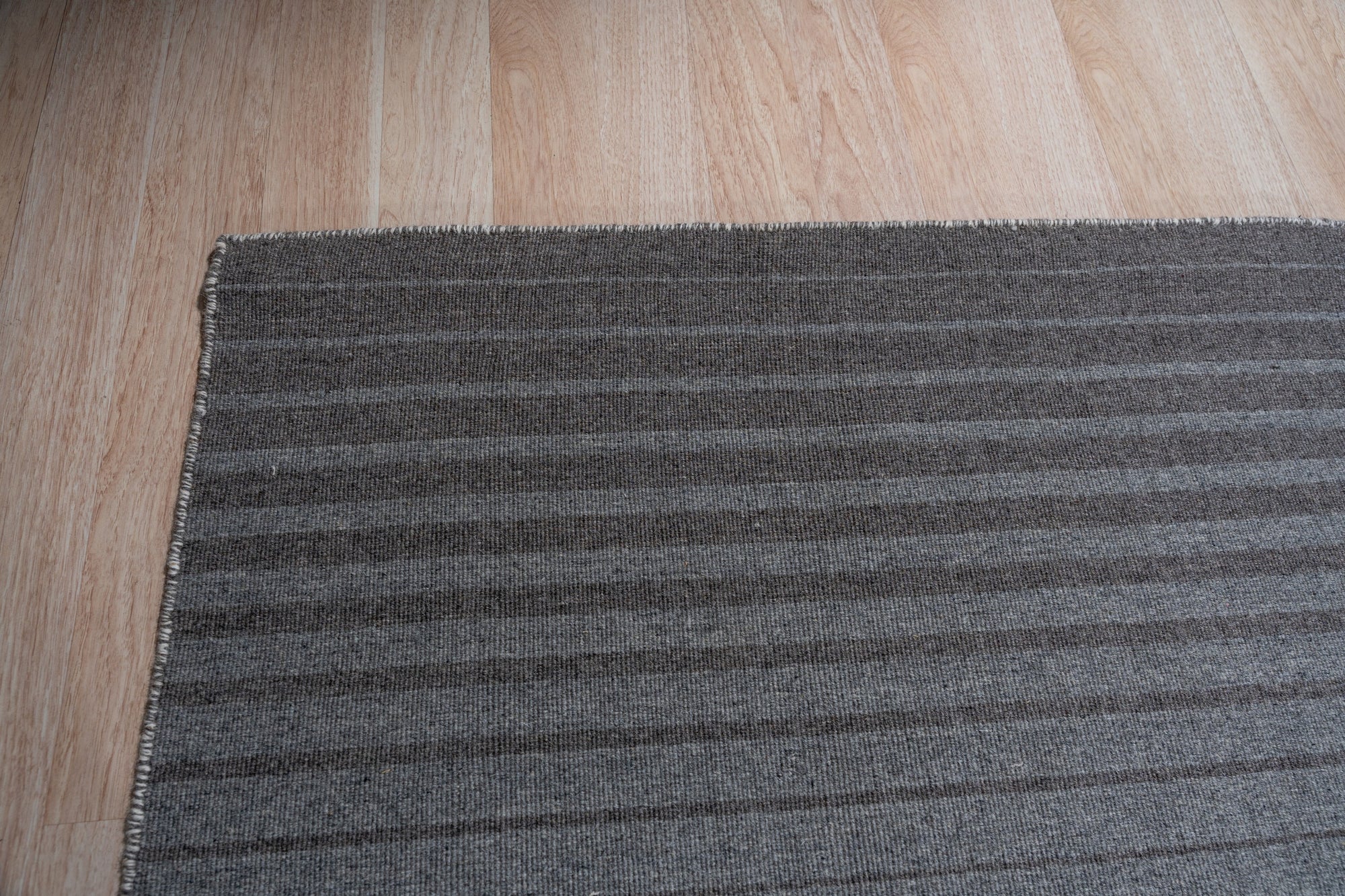 Timeless Comfortable Gray Flatweave Wool Rug, seen in a bright, inviting living room setting. Natural light highlights the subtle texture and cool gray tones of this flatweave wool rug, grounding a contemporary space.