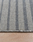 Timeless Comfortable Gray Flatweave Wool Rug lies elegantly on a hardwood floor, its subtle gray tones complementing a minimalist interior. Notice the flatweave construction allowing for a low profile, ideal for high-traffic areas, hinting at both durability and comfort.