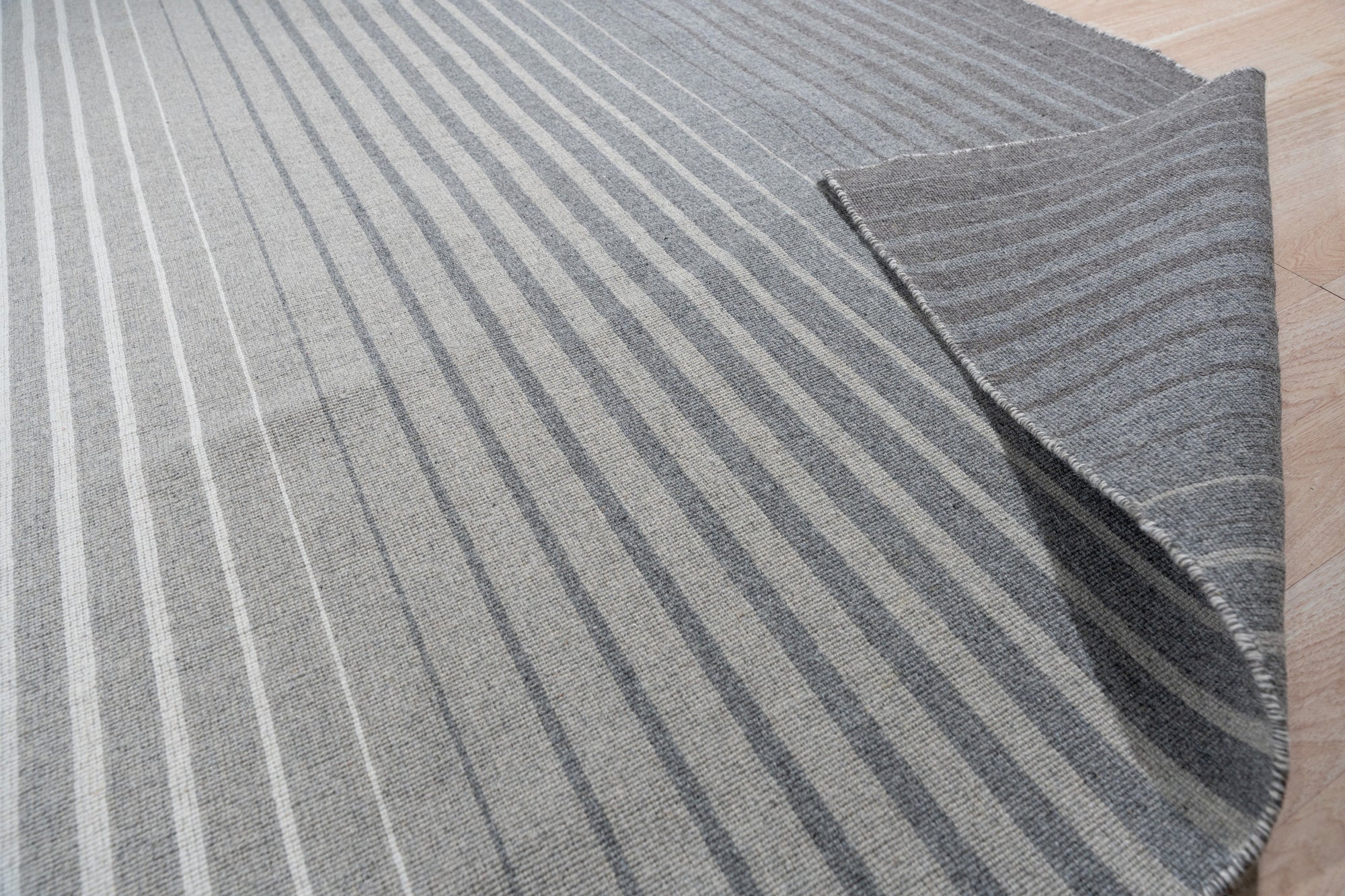 Timeless Comfortable Gray Flatweave Wool Rug, a calming expanse of gray wool with a subtle texture, anchors a bright living room with neutral-toned furniture and natural light.