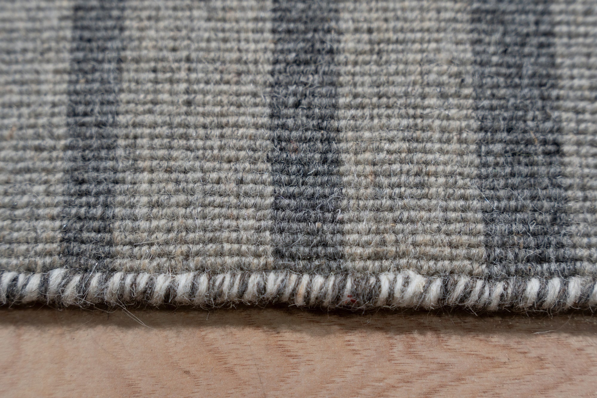 Timeless Comfortable Gray Flatweave Wool Rug graces a bright, modern living room. Light filters across its subtle, textural flatweave, showcasing the rug's soft gray tones and comfortable wool construction within a casually elegant space.