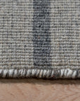 Timeless Comfortable Gray Flatweave Wool Rug graces a bright, modern living room. Light filters across its subtle, textural flatweave, showcasing the rug's soft gray tones and comfortable wool construction within a casually elegant space.