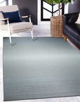 Timeless Comfortable Gray Flatweave Wool Rug anchors a modern living space, its subtle gray tones complementing light wood floors and crisp white walls. The flatweave construction is evident, showcasing a smooth, low-profile texture. Natural light highlights the rug's warmth and inviting comfort.