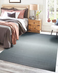 Timeless Comfortable Gray Flatweave Wool Rug, its subtle texture adding warmth to a bright, modern living room. Light wood furniture and natural light highlight the rug's soft gray tones and simple elegance.