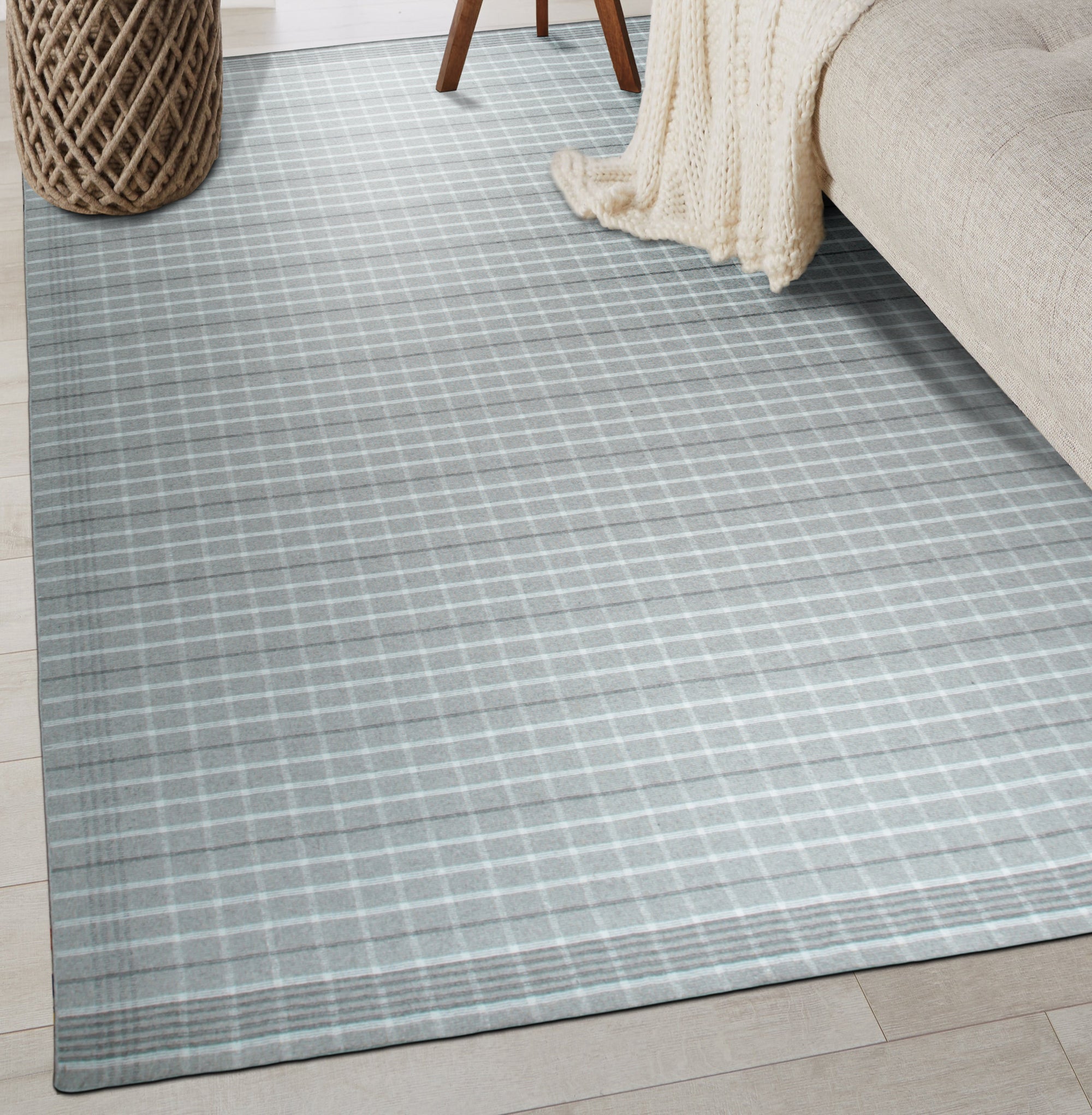 Timeless Celia Gray Flatweave Wool Rug, showcasing a geometric pattern in shades of gray and cream, laid on a light wood floor in a bright, modern living room setting.