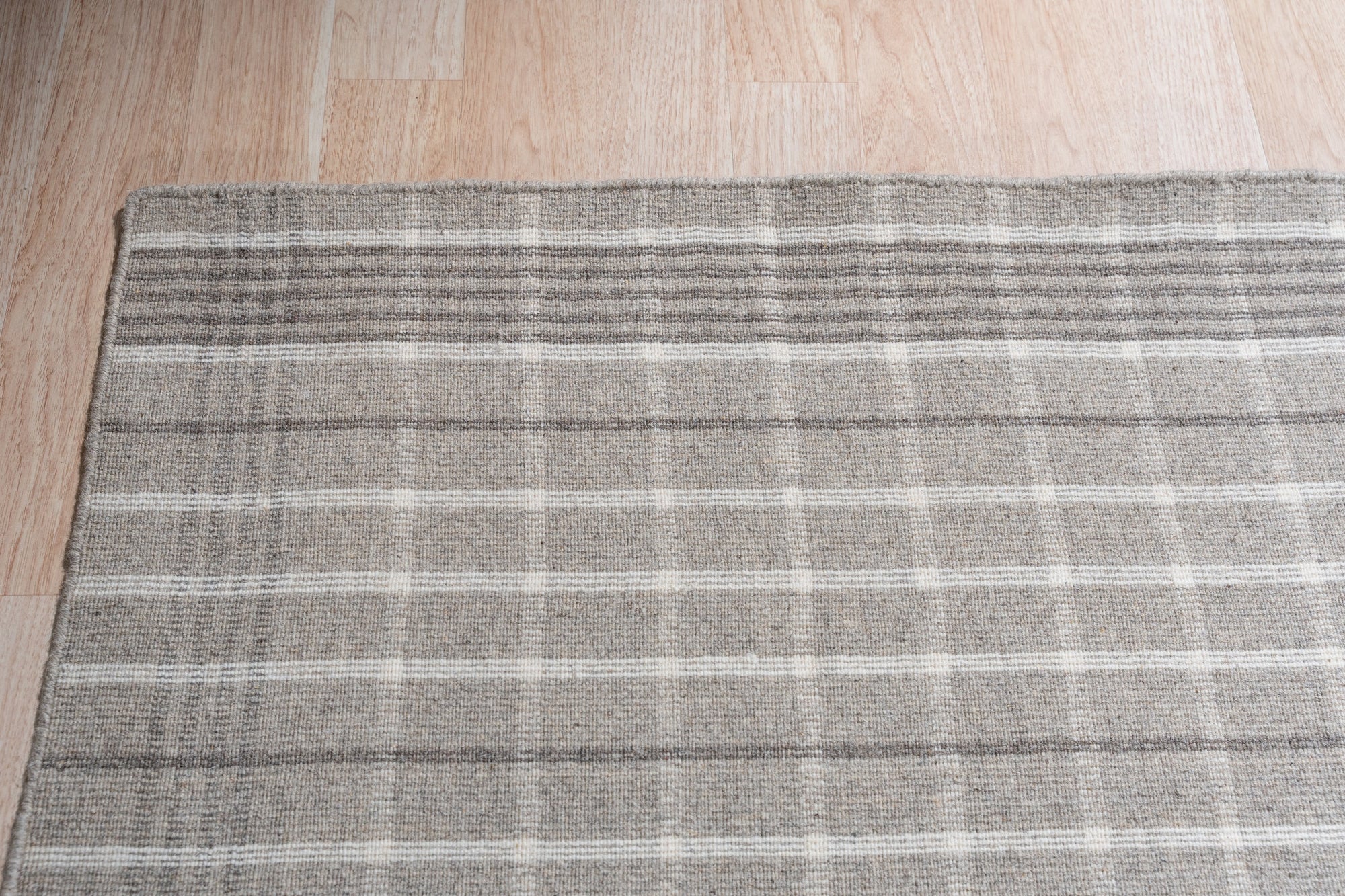 Timeless Celia Gray Flatweave Wool Rug, a muted gray flatweave wool rug subtly textured, seen in a bright, contemporary living room setting.