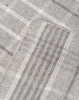 Timeless Celia Gray Flatweave Wool Rug graces a light wood floor in a bright, modern living room; its subtle geometric pattern and soft gray hues complement the minimalist aesthetic.