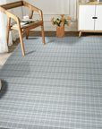 Timeless Celia Gray Flatweave Wool Rug, a soft gray wool rug with a subtle, geometric pattern, complementing a modern living room setting with light wood furniture and natural light.