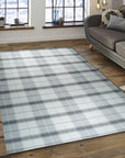 Lila Bianca Gray Flatweave Wool Rug displayed in a bright, modern living space. The gray and white wool rug anchors a seating area with a light-colored sofa and wooden coffee table, showcasing its simple, elegant design.