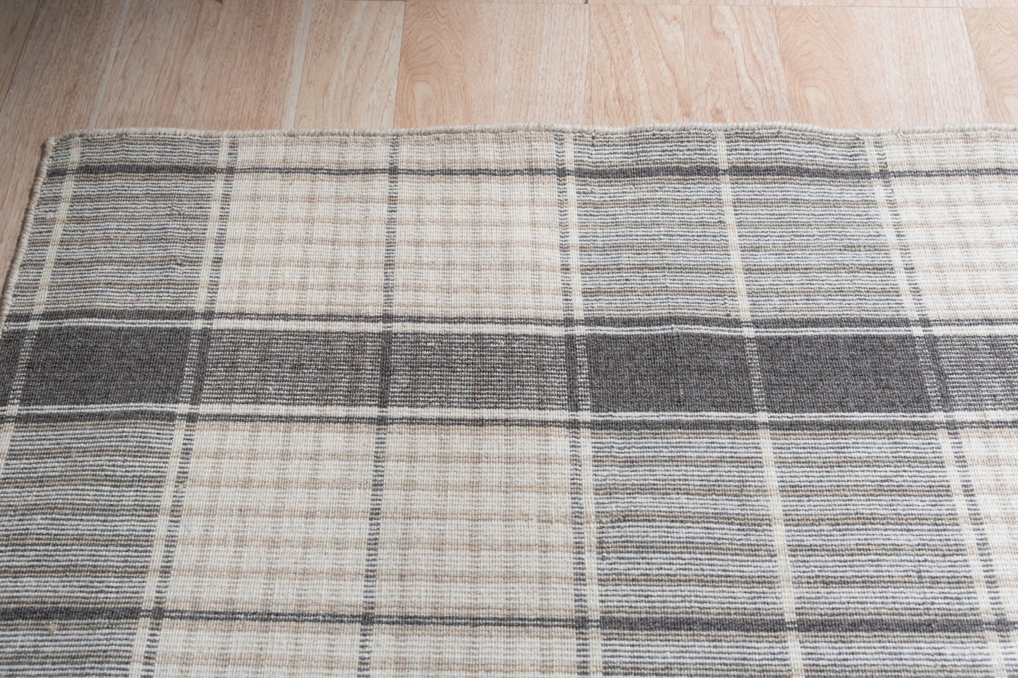 Lila Bianca Gray Flatweave Wool Rug, a calming gray and cream geometric pattern, adds understated elegance to a modern living room with minimalist furniture.