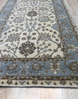 Opulent Oushak Ivory Hand Knotted Wool Rug, with a subtle ivory palette and intricate floral design, sprawls across a light-filled room, its hand-knotted wool texture adding warmth and luxury.