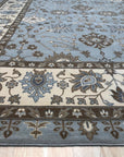 Artisan Oushak Light Blue Hand Knotted Wool Rug, showcasing a light blue palette and intricate Oushak design, softens a bright, sunlit room.