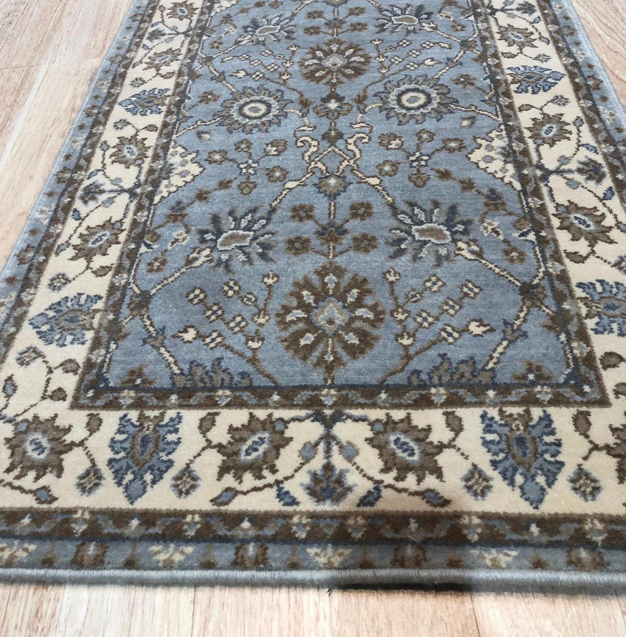 Artisan Oushak Light Blue Hand Knotted Wool Rug, its light blue field showcasing intricate floral patterns and a delicate border, lending a touch of serene elegance to a styled living room setting.