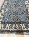 Artisan Oushak Light Blue Hand Knotted Wool Rug, its light blue field showcasing intricate floral patterns and a delicate border, lending a touch of serene elegance to a styled living room setting.