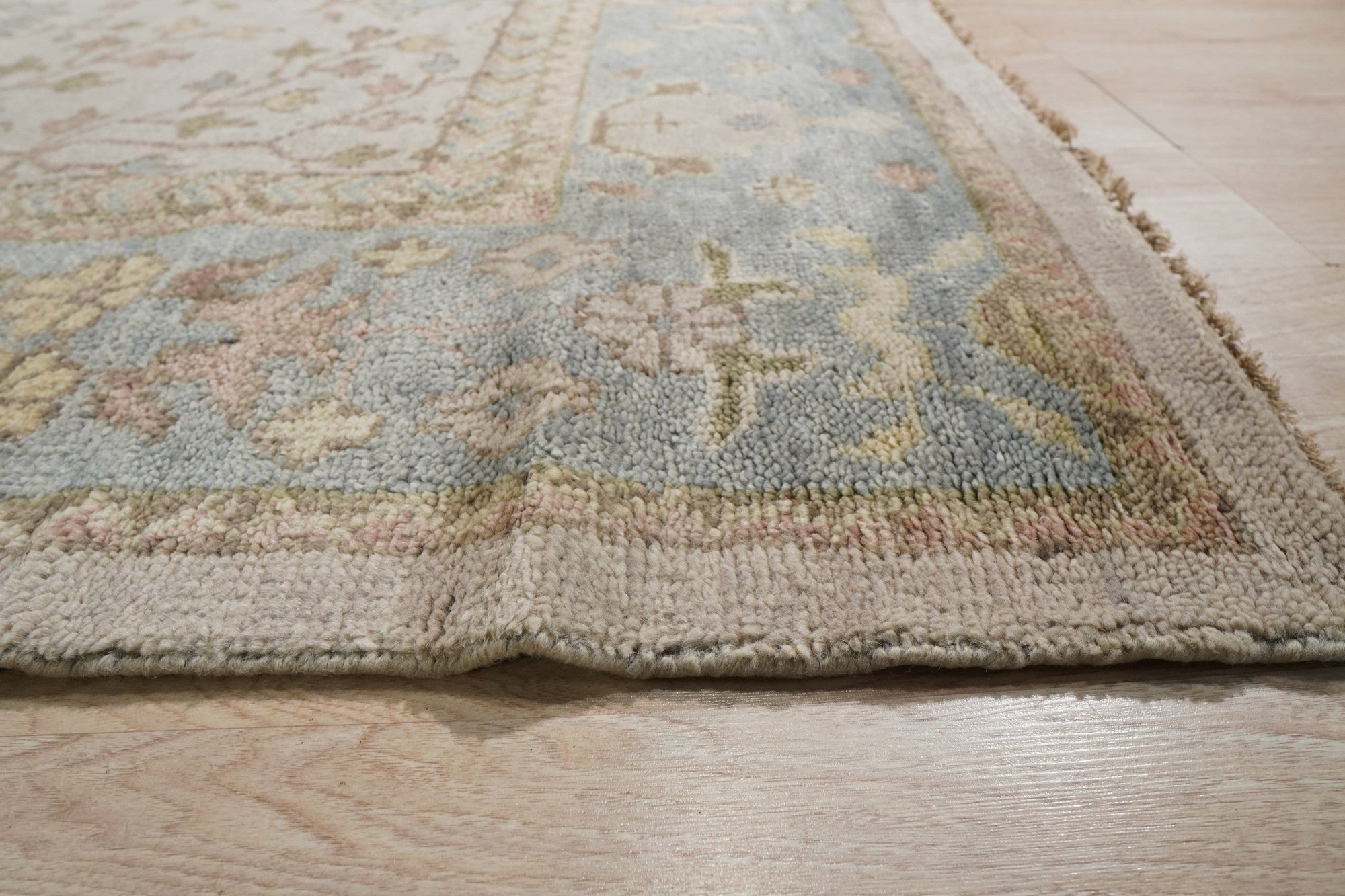 Classic Oushak Beige Hand Knotted Wool Rug displayed in a living room setting, its subtle beige tones complementing the surrounding furniture and lending warmth to the space.