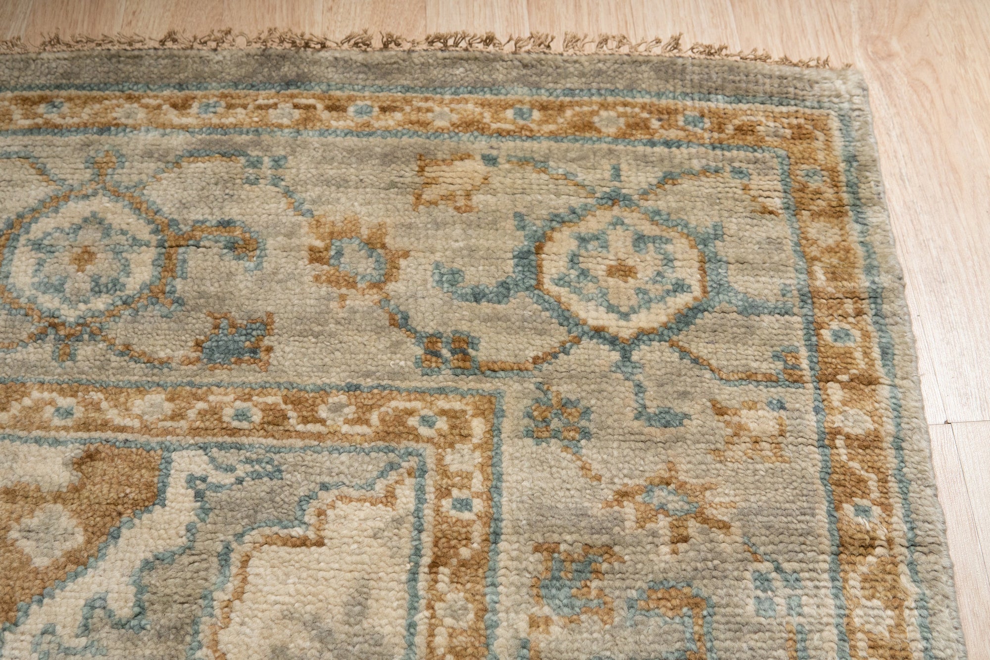 Freya Oushak Green Hand Knotted Wool Rug nestled in a bright, inviting living room; its hand-knotted wool construction and soft green hues anchor a space filled with natural light and modern furniture.