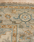 Freya Oushak Green Hand Knotted Wool Rug nestled in a bright, inviting living room; its hand-knotted wool construction and soft green hues anchor a space filled with natural light and modern furniture.