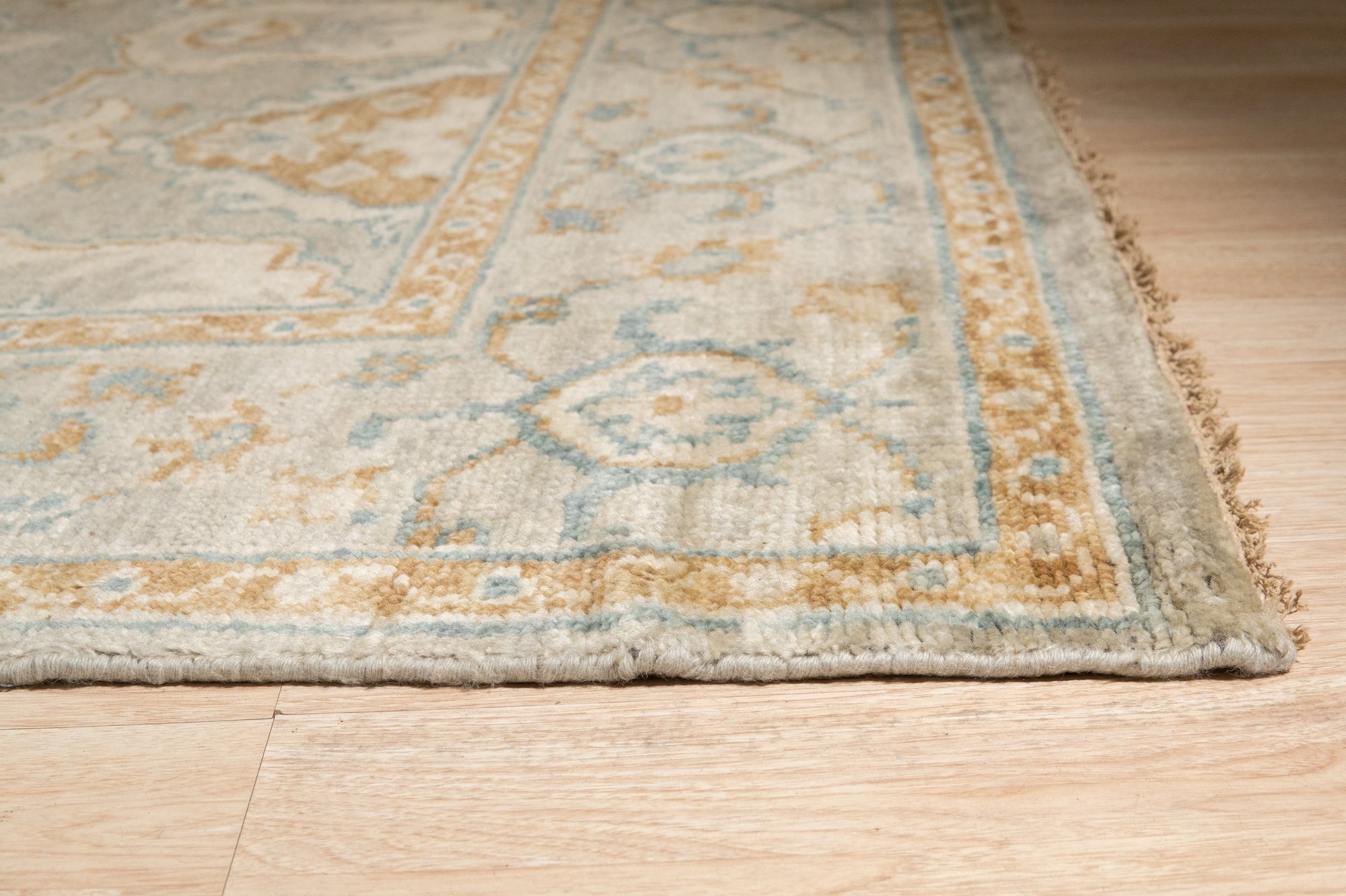 Freya Oushak Green Hand Knotted Wool Rug, a verdant expanse of handcrafted wool featuring a traditional Oushak pattern, graces a warmly lit living space.