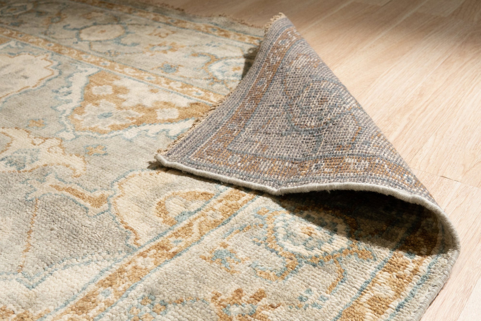 Freya Oushak Green Hand Knotted Wool Rug, its verdant hues and intricate floral patterns gracefully unfurling across a softly lit floor, inviting warmth and artisanal charm into the space.