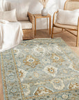 Freya Oushak Green Hand Knotted Wool Rug, a calming green wool rug with intricate floral motifs and a subtly distressed texture, adding warmth and elegance to a well-lit living space.