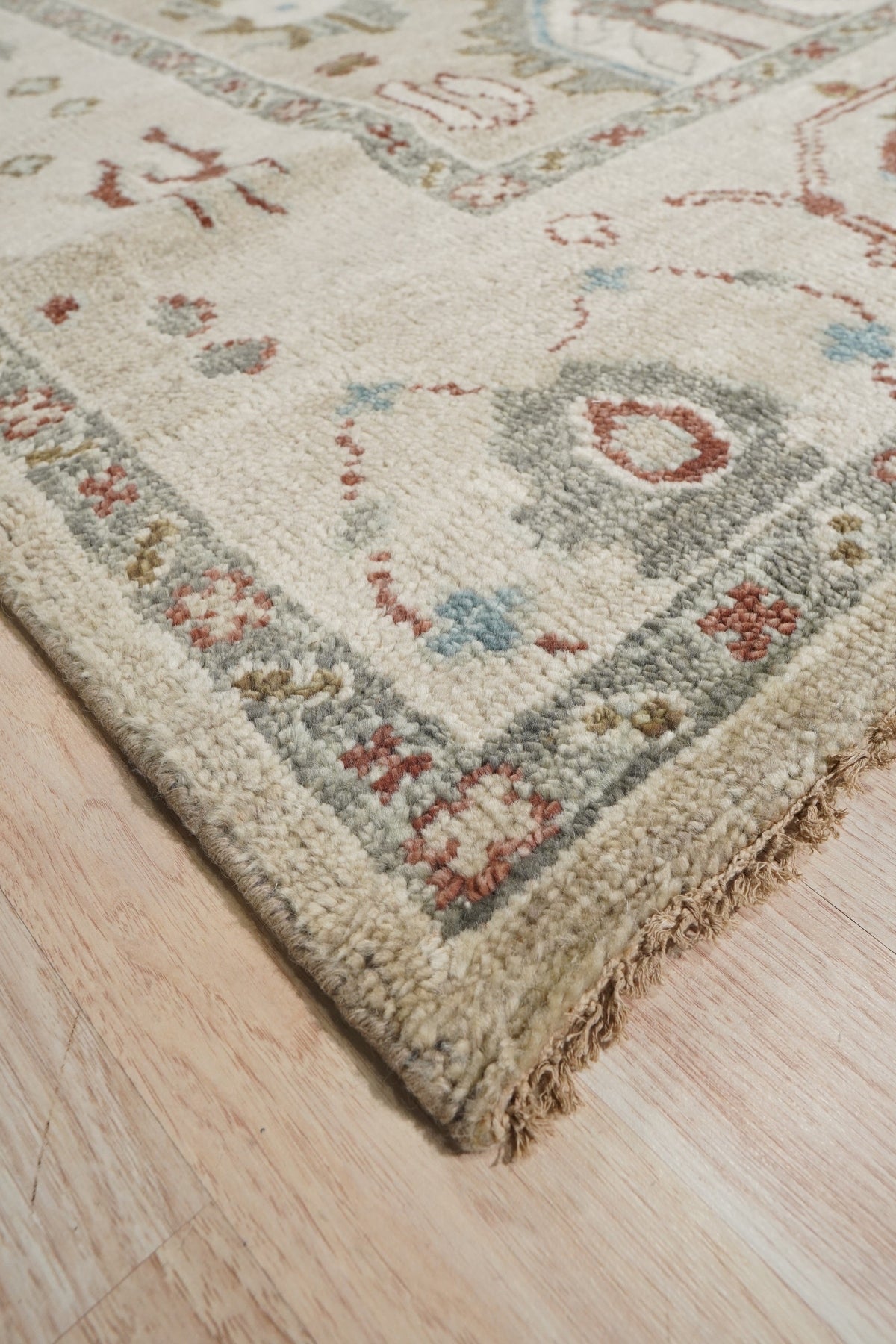 Versatile Oushak Ivory Hand Knotted Wool Rug gracing a light-filled living space, its soft ivory tones and traditional Oushak pattern lending warmth and subtle elegance to the room.