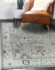 Versatile Oushak Ivory Hand Knotted Wool Rug, an ivory and muted-tone wool rug with a traditional, subtly distressed design, lays elegantly on a hardwood floor in a brightly lit room.