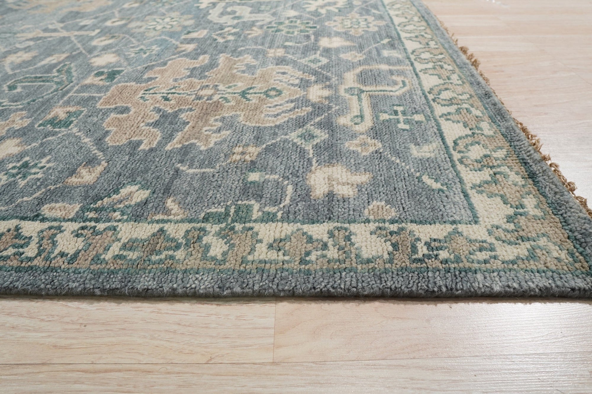 Beautiful Oushak Blue Hand Knotted Wool Rug, its intricate floral patterns and soft blue hues complementing a bright, airy living room setting.