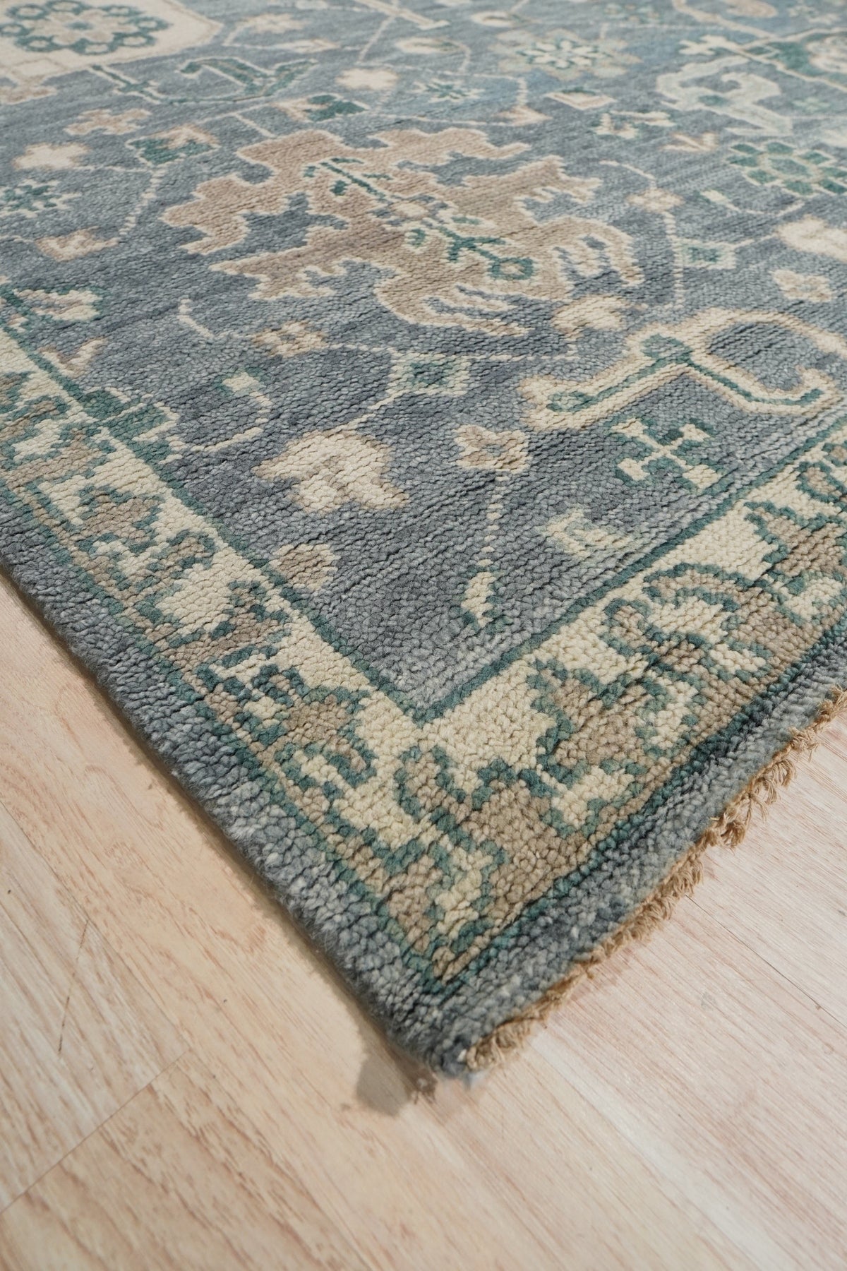 Beautiful Oushak Blue Hand Knotted Wool Rug, its intricate floral patterns and soft blue hues creating a serene atmosphere in a bright living room setting.