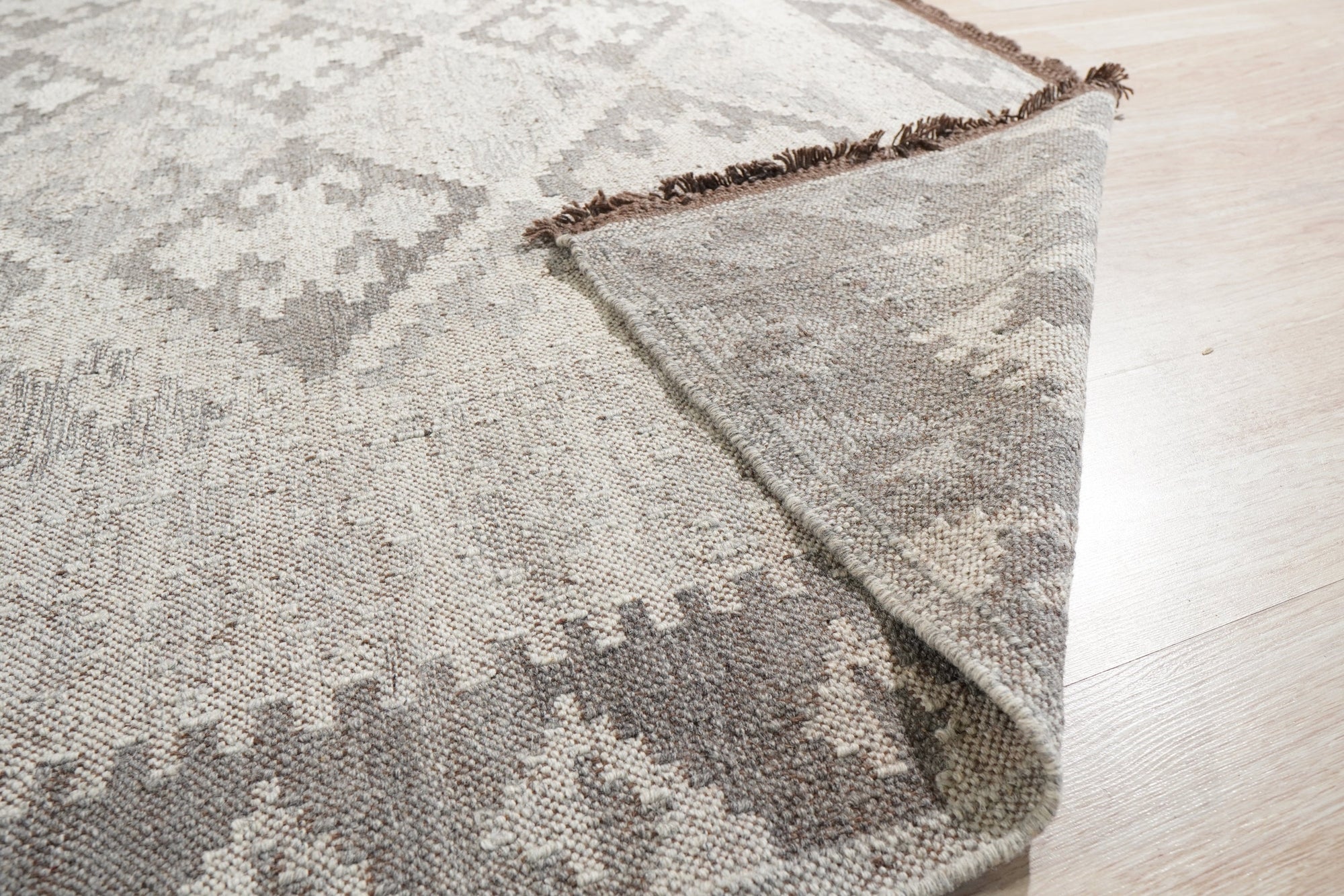 Brenda Para Gray Flatweave Wool Rug in a bright, modern living room, its subtle gray tones complementing the light wood floors and minimalist furniture. Soft texture and flatweave construction invite comfortable living.