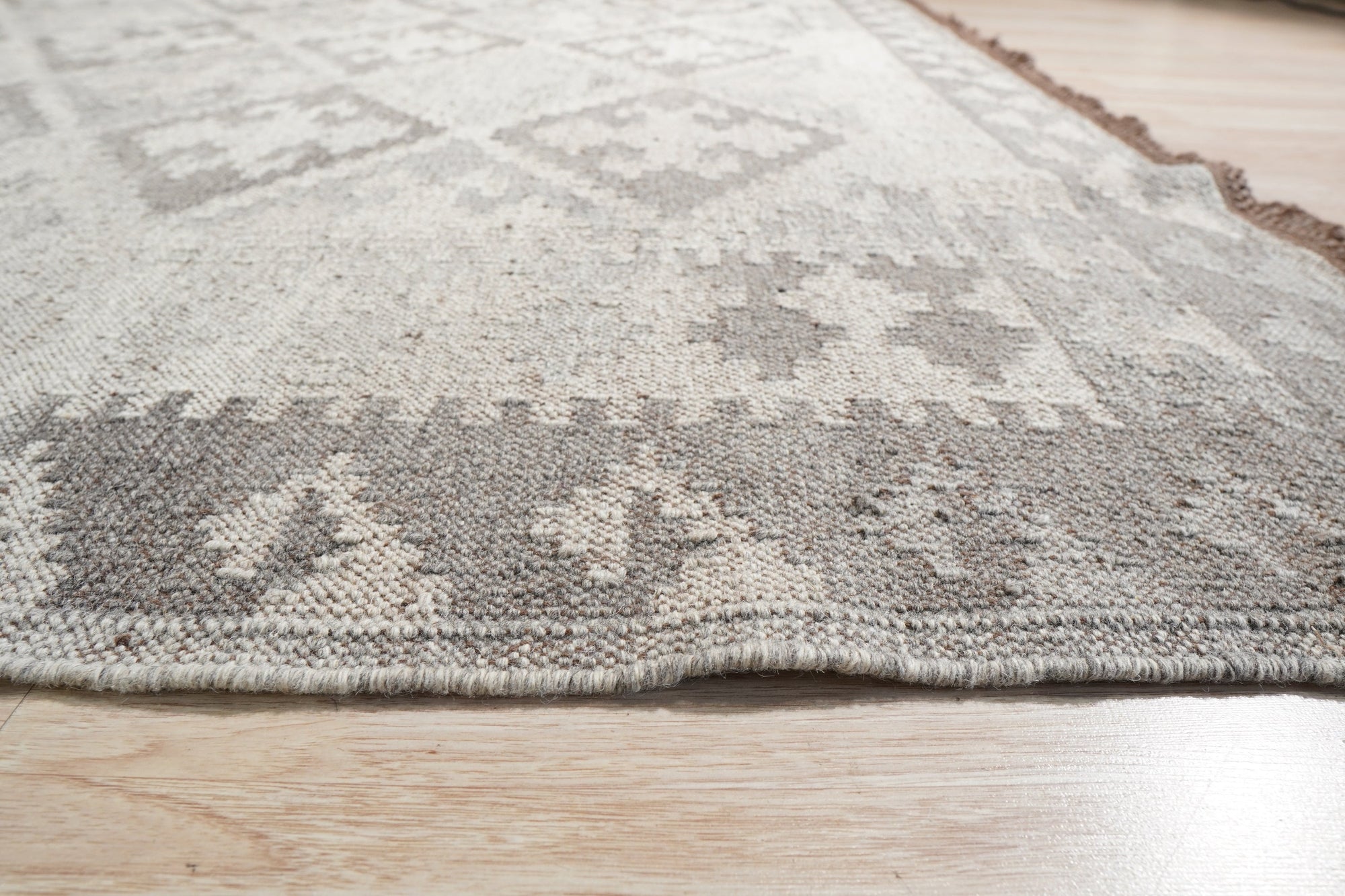 Brenda Para Gray Flatweave Wool Rug, blending seamlessly into a bright living room with natural light, its flatweave construction displaying subtle geometric patterns in shades of gray and off-white.
