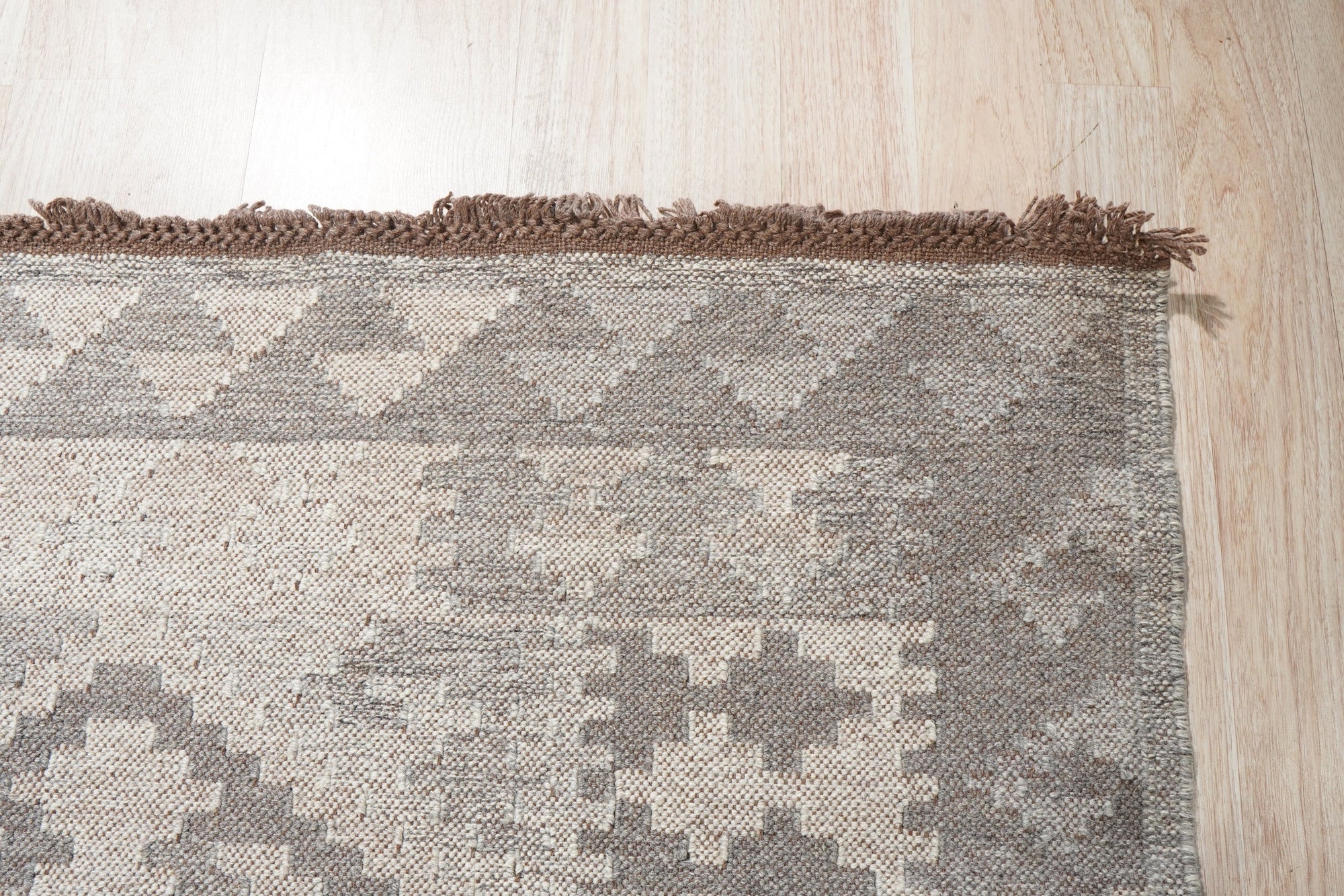 Brenda Para Gray Flatweave Wool Rug, soft gray tones and subtle woven texture, lies centered in a bright, modern living room; sunlight catches the rug’s surface, highlighting the flatweave construction.