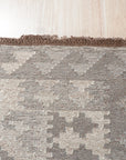 Brenda Para Gray Flatweave Wool Rug, soft gray tones and subtle woven texture, lies centered in a bright, modern living room; sunlight catches the rug’s surface, highlighting the flatweave construction.